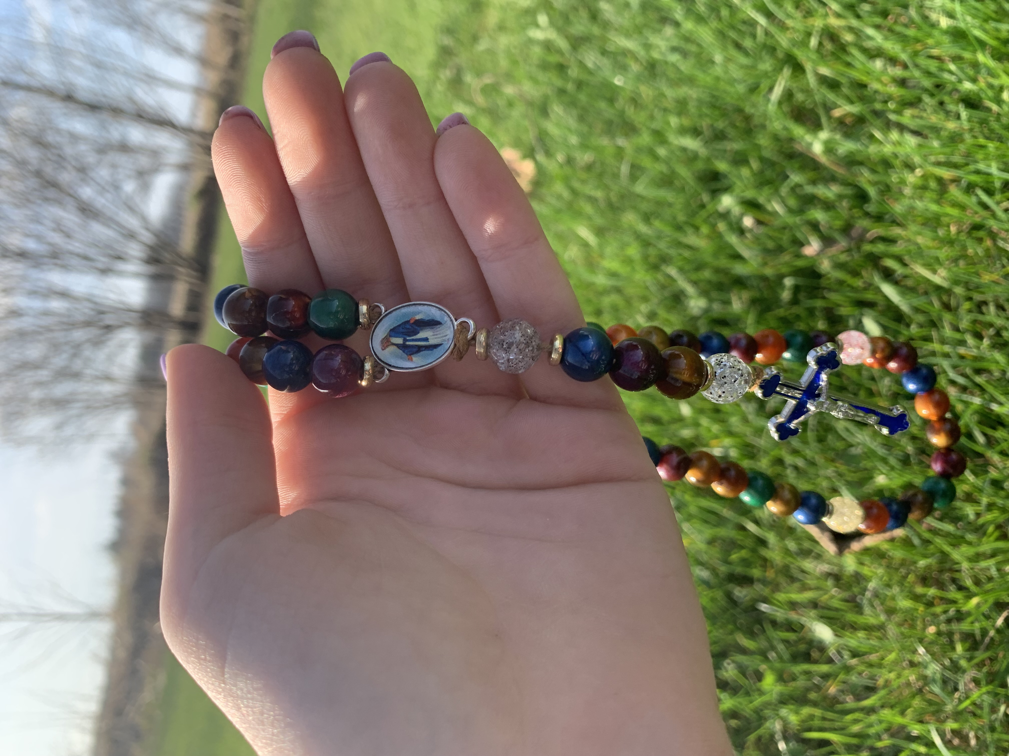 A picture of someone holding the rosary outside.